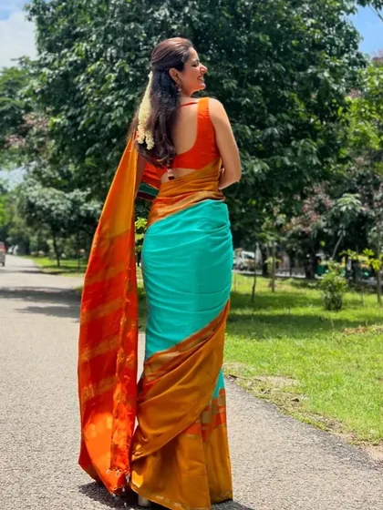 The gorgeous Ashika Ranganath in a custom sleeveless blouse I designed. The vibrant orange provides a stunning contrast to her turquoise and gold saree.