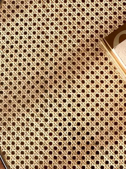 A detailed close-up of the intricate cane weaving on the coffee table. This traditional craft requires great skill and attention to detail.