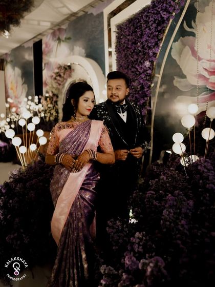 A dramatic and elegant portrait of the couple at their reception, surrounded by a lavish purple floral decor.