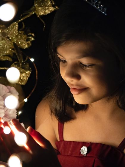 A magical, low-light portrait using fairy lights to create a dreamy effect. This demonstrates our creative approach to lighting, even in an outdoor setting, to produce unique and artistic photos.