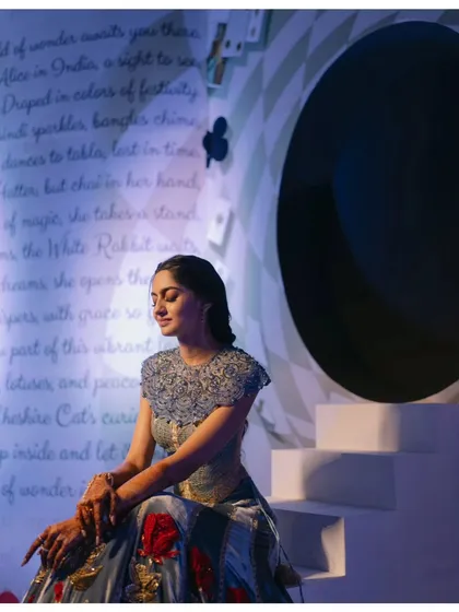 The bride takes a quiet moment, seated by the storybook backdrop. The dramatic lighting and unique setting create a truly memorable portrait.