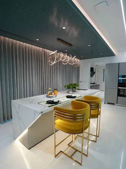 The island in the dry kitchen features a waterfall countertop and is paired with chic, modern bar stools, creating a perfect spot for guests to gather.