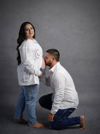 A classic maternity pose with the partner kissing the baby bump, all while keeping the vibe casual and sweet.