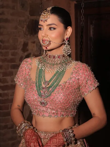 A close-up of the Anand Karaj bride's stunning makeup and jewellery. The focus is on her luminous skin and the intricate details of her nath and layered necklaces.