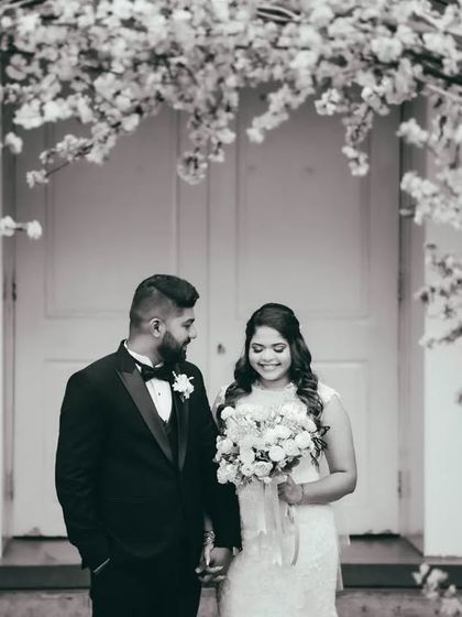 A beautiful black and white portrait of the couple framed by a floral arch. This is a classic and elegant post-ceremony photograph.