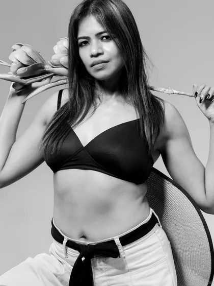 A strong black and white portrait with a floral prop. The contrast between the soft flower and the model's confident expression is the focus.