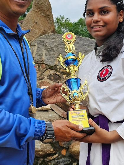 The smile of success. This student's hard work is rewarded with a championship trophy, a proud moment for her and the entire academy.