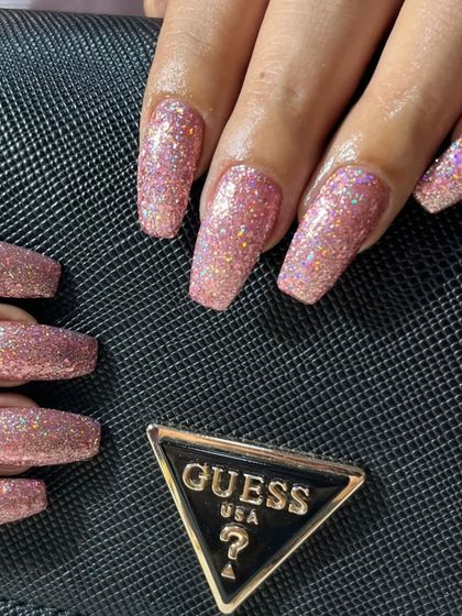 A close-up of the pink glitter nails against a black handbag, showing how they can be the perfect glamorous accessory.