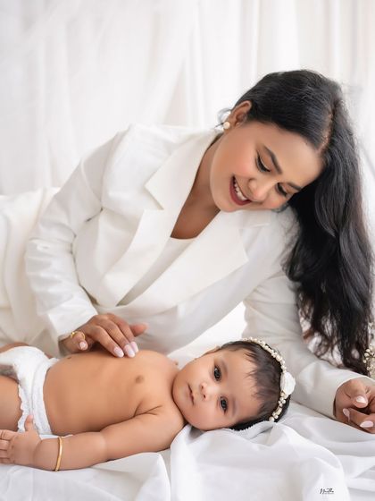 A stylish mother in a white suit looking lovingly at her baby.