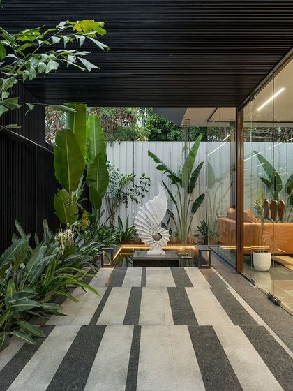 A pathway at the Soul Spring center, where striped paving guides movement alongside a glass-walled lounge. A sculptural piece on a water feature acts as a destination and point of interest.