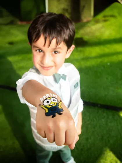 Fun at a birthday party. This candid shot captures a boy proudly showing off his Minion hand tattoo.