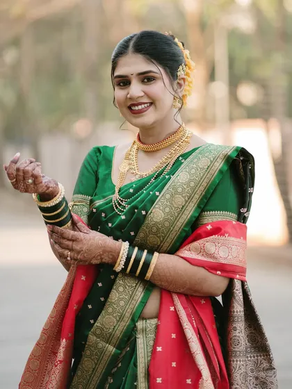 A beautiful portrait of a Marathi bride, her joy evident in her smile. We captured her adjusting her bangles, a simple gesture that adds a touch of candid grace to the shot.