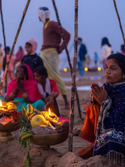 On the riverbank, a family performs Chhath Puja rituals with offerings and diyas, showcasing the communal aspect of this important Bihari festival.