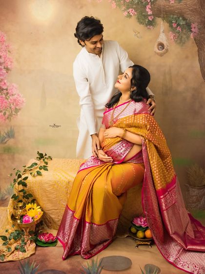 A romantic and gentle portrait of a couple. The husband-to-be stands behind his seated wife, creating a composition filled with love, support, and anticipation.