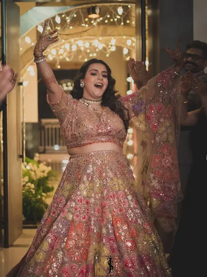 The grand entrance! This photo captures the energy and happiness of the Sangeet night. The lehenga was designed for movement, allowing her to dance the night away with ease.