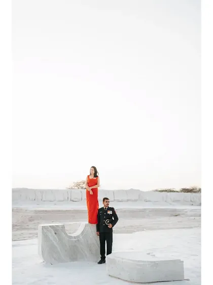 A powerful, statuesque pose from the army uniform and red dress shoot, creating a visually stunning and symbolic image.