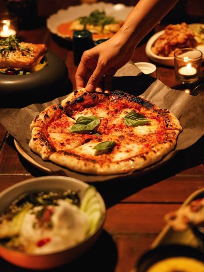 A close-up of our classic Margherita pizza, with its blistered crust and fresh basil, a testament to simple, delicious food.