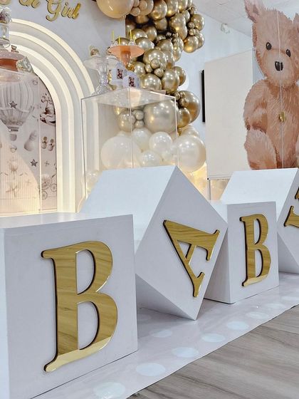 Large white 'BABY' blocks with gold lettering provide a classic and bold element to the stage design, perfect for photos.