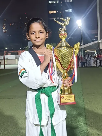 This young green belt proudly holds her first-place trophy. Her hard work and fighting spirit shone through in the competition.