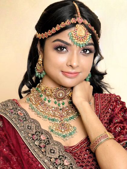 A classic portrait of a model wearing our green Kundan reception set. The hand-on-chin pose highlights the matching bracelet.