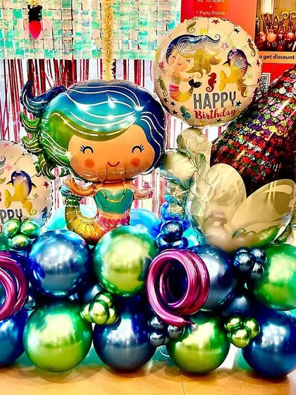Making a splash with this magical mermaid balloon bouquet. The shimmering chrome balloons in green and blue, paired with a large mermaid tail and character balloon, create a stunning centerpiece for any underwater-themed party.