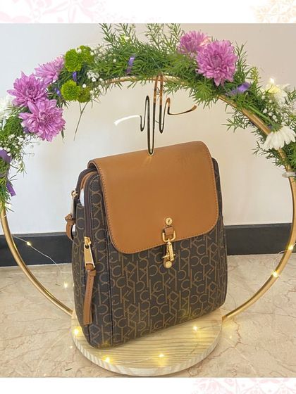Presenting luxury accessories with flair. This Calvin Klein backpack is displayed on a custom golden ring stand adorned with fresh flowers and fairy lights, making the gift itself an experience.