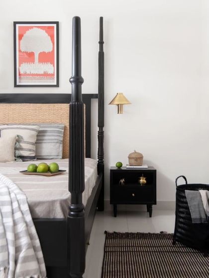 The bedside vignette in the primary bedroom, showing the curated selection of art and decor that adds a personal touch to the neo-traditional design.