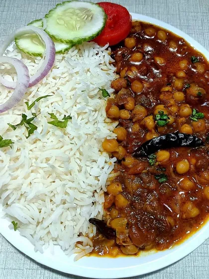 A plate of my classic Chole Chawal, a favorite for any community feast. I serve it with fluffy basmati rice and a fresh salad, making it a complete and satisfying meal for your guests.