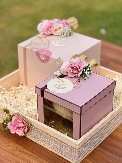 Bespoke return favours designed to share sweetness. These gift boxes, presented in a rustic wooden tray, feature our signature pink packaging, floral toppers, and custom tags, creating a warm and inviting thank you gift for guests.