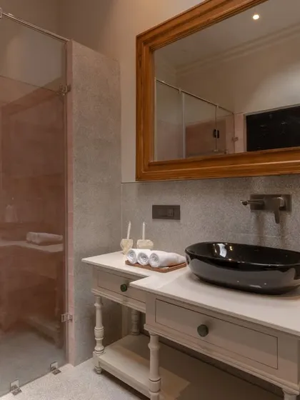 This bathroom from the Buransh Terraces project features a classic vanity paired with a modern black vessel sink. The large wood-framed mirror adds warmth and reflects the light, making the space feel bright and airy.
