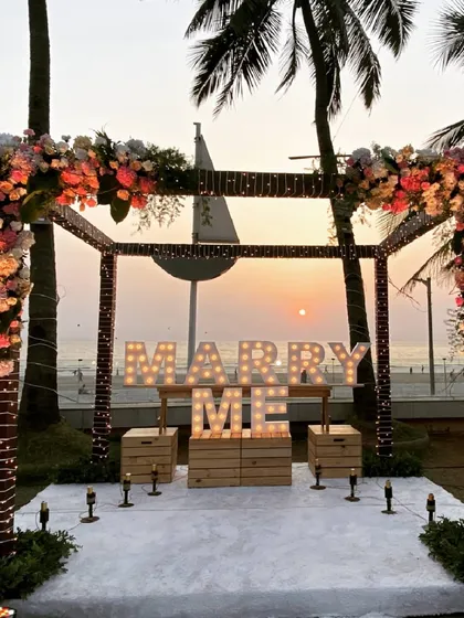 Your love story deserves a magical beginning. We set up this romantic sea-facing proposal at sunset, complete with a floral arch, a candlelit path, and marquee lights spelling out the most important question.
