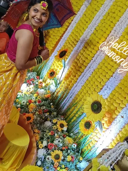 The bride posing with a small umbrella prop, with the sunflower and marigold backdrop creating a perfect photo opportunity.