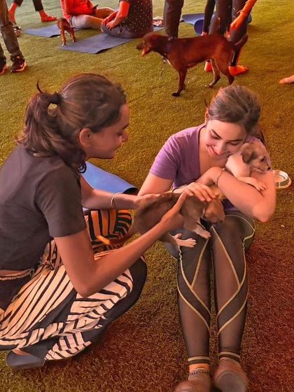 Two participants share a moment of joy, cuddling with tiny, adorable puppies during a break in their yoga class.