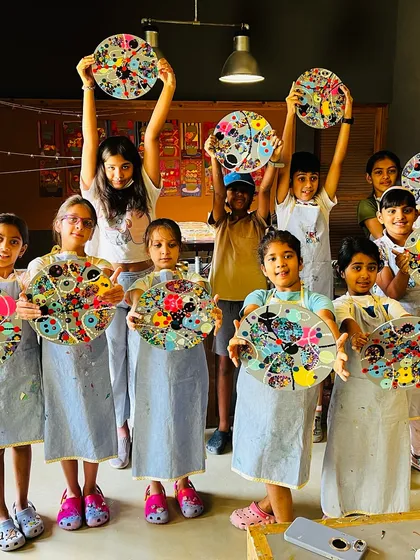 A happy class shows off their abstract circle paintings, a project that explores color theory and composition.