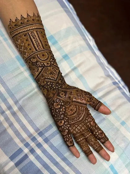 A classic engagement henna design with geometric patterns and bands covering the full arm.