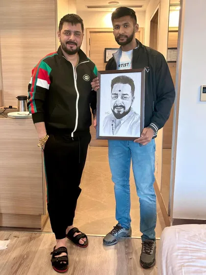 A full-length photo with Hindustani Bhau and the framed portrait I created for him.