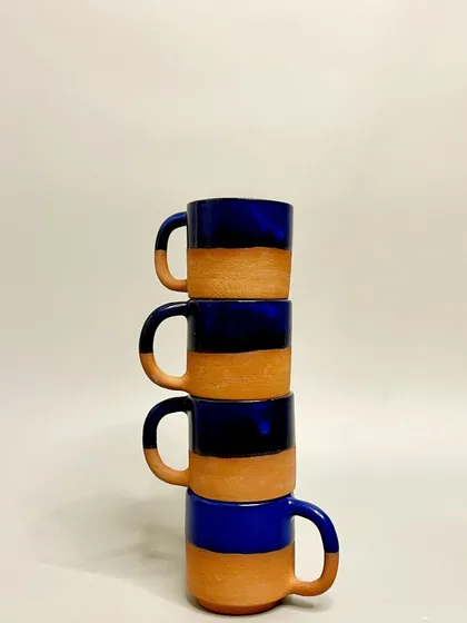 A stack of my cobalt blue and terracotta mugs. The vertical arrangement highlights their uniform shape, a result of careful craftsmanship, while the handmade nature ensures each has its own subtle character.