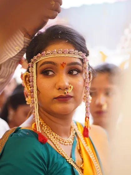 A close-up of the bride during a ceremony, framed by the antarpat. This shot highlights the precision of the eye makeup and the traditional bindi.