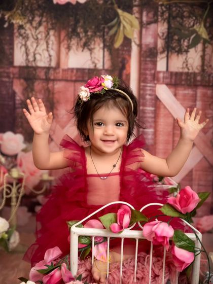 A happy toddler waves to the camera during her fun and colorful first birthday session.