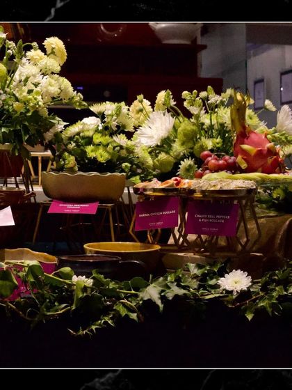 A bespoke grazing table with a wide array of options, from charcuterie and cheese to bite-sized Indian snacks and canapés, all beautifully arranged with floral decorations.