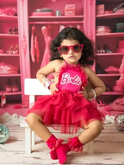 It's a Barbie world, and this little one owns it. My Barbie-themed shoots are all about capturing that fun, confident personality with a vibrant pink set and stylish props like these heart-shaped sunglasses.