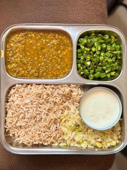A wholesome plate of brown rice, whole green gram dal, sautéed beans, and cabbage, with a side of curd.