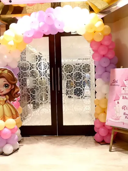 The entrance decor for the princess party, featuring a pastel balloon arch and a welcome sign on an easel.