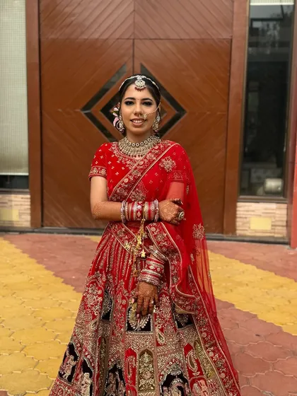 A full-length shot of the bride, looking every bit the part of a traditional queen. The makeup is designed to complement the intricate details of her lehenga.
