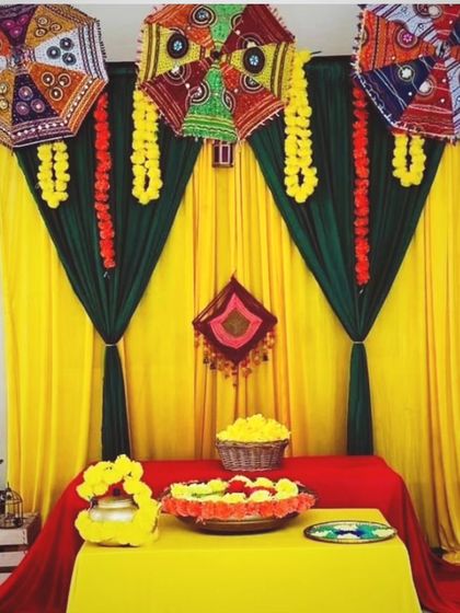 An elegant Mehendi corner setup with a decorated table, marigold flowers, and a beautiful backdrop with umbrellas.