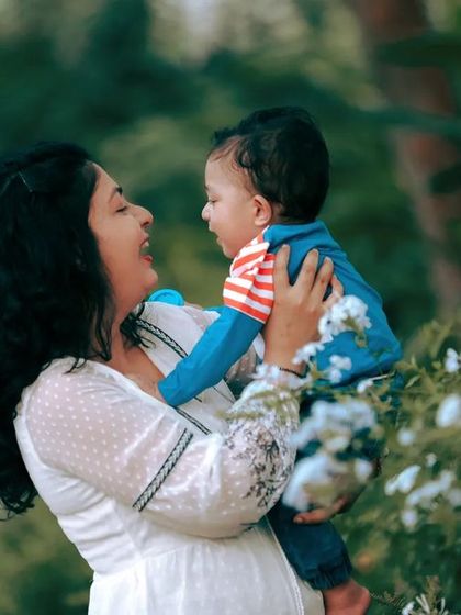 A mother laughing with her baby in a beautiful garden setting. This candid shot perfectly captures the joy and connection between them.