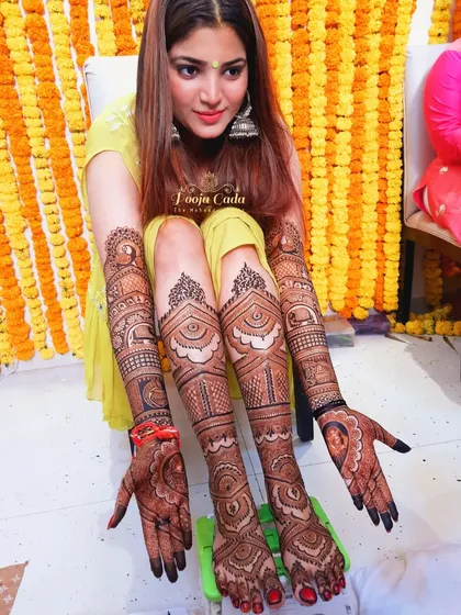 A heavy bridal mehendi look, with intricate designs covering the bride's hands, arms, legs, and feet for a truly stunning effect.