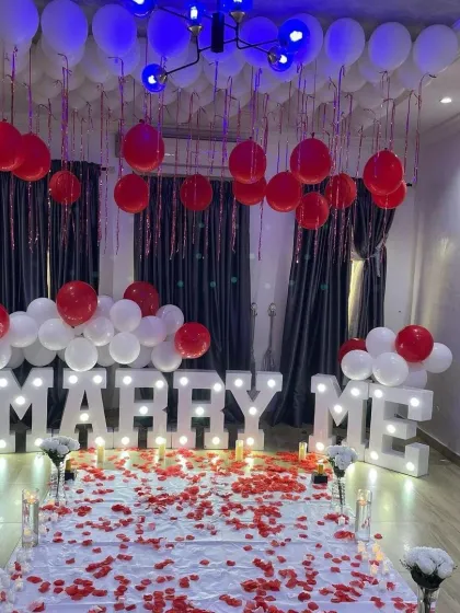 We help you pop the question in style with our romantic proposal setups, featuring large 'MARRY ME' marquee letters, a path of rose petals, and ceiling balloons.