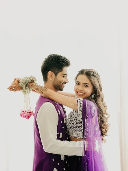 A bright and joyful portrait against a clean white background. The bride's happy smile as she hugs the groom from behind makes for a fresh, modern, and heartwarming shot.