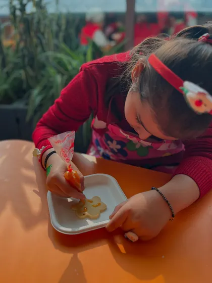 A student is deeply focused on decorating a Christmas cookie with icing. Our workshops always include a mix of activities, including delicious edible art!